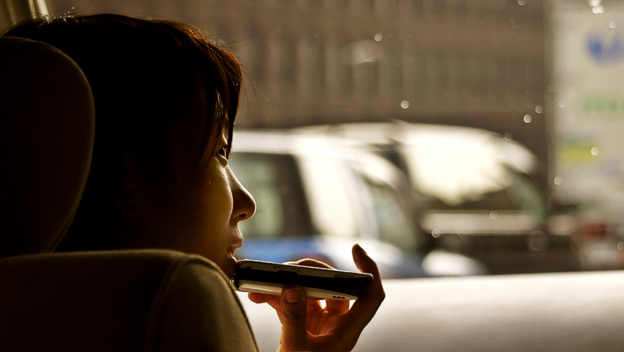 Woman talks on a phone while in car.