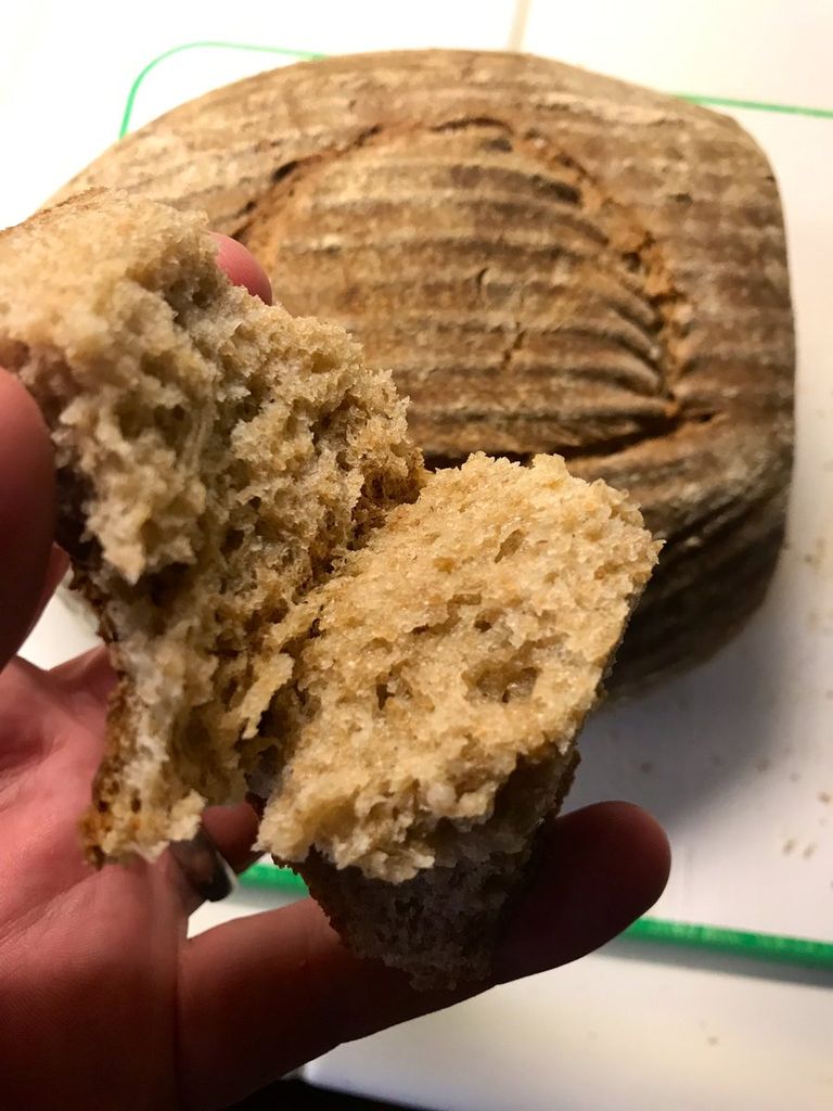 The finished bread - a slice in the hand, the loaf in the background.