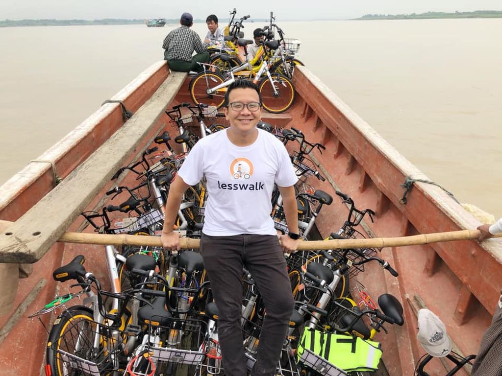 Mike Than Tun Win in front of wooden boat full of bikes.