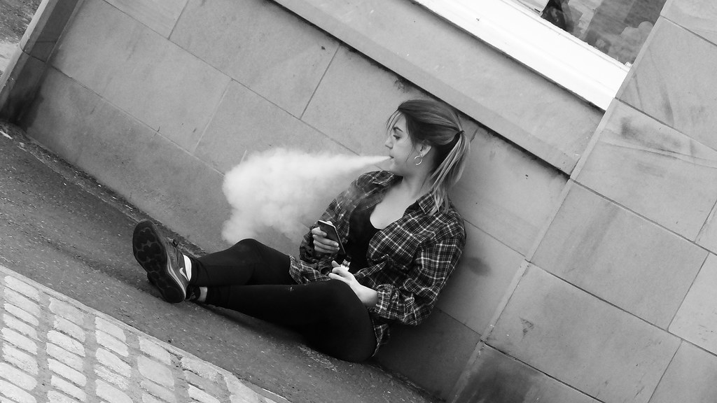 Woman sitting and exhaling after vaping.