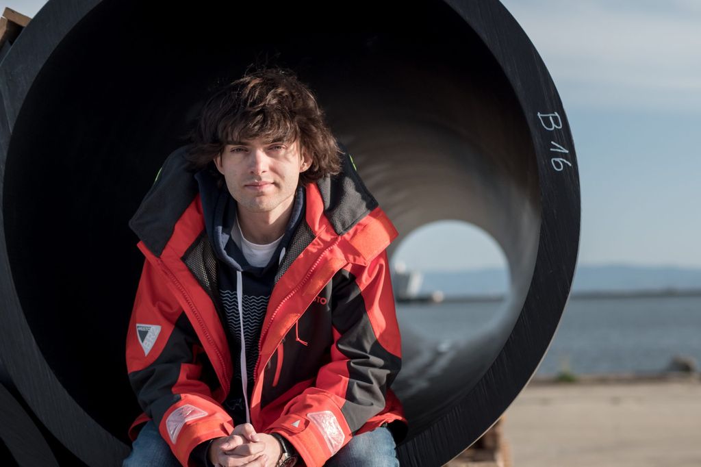 Boyan Slat, the inventor of the Ocean Cleanup sits on the edge of a tube used in the project.