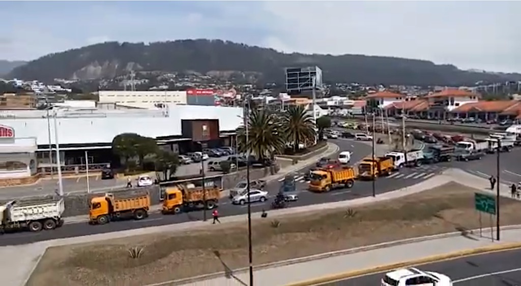 Picture is from a video of a long line of trucks moving very slowly to block traffic.