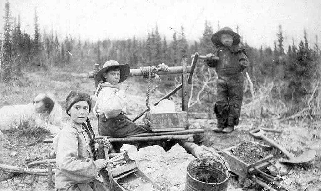 Three children operating rocker at a gold mine on Dominion Creek, Yukon Territory, ca. 1898