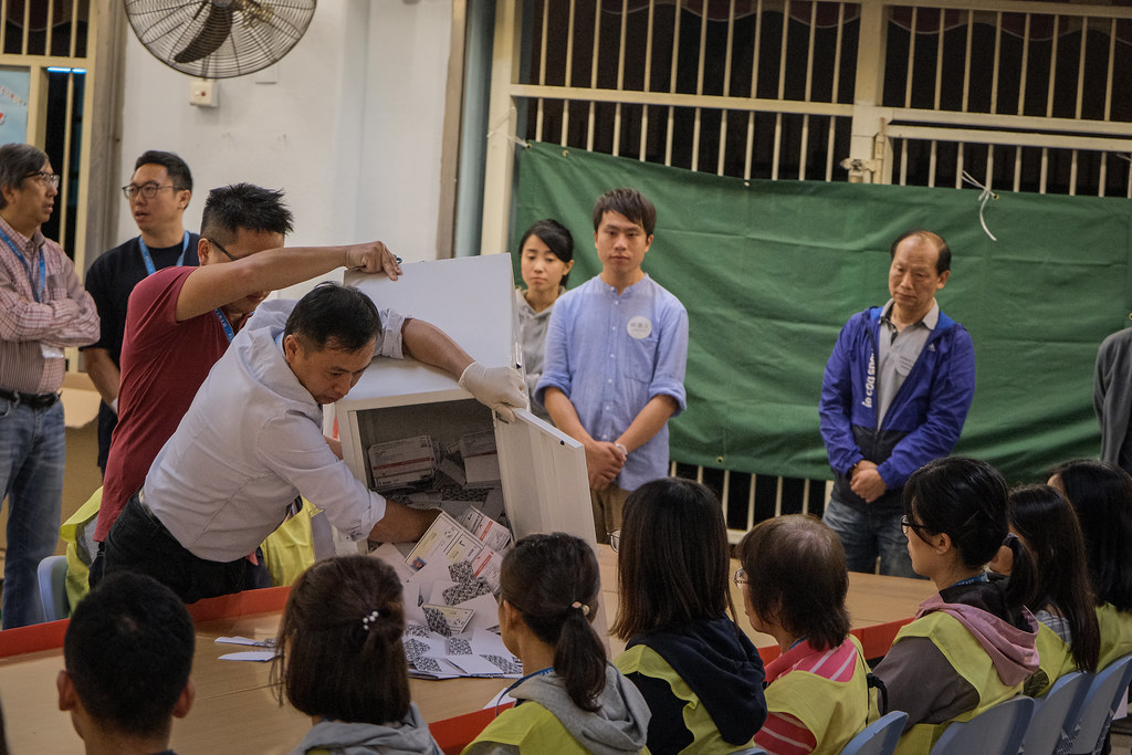 Worker dumping ballots out of a ballot box for counting in Hong Kong.