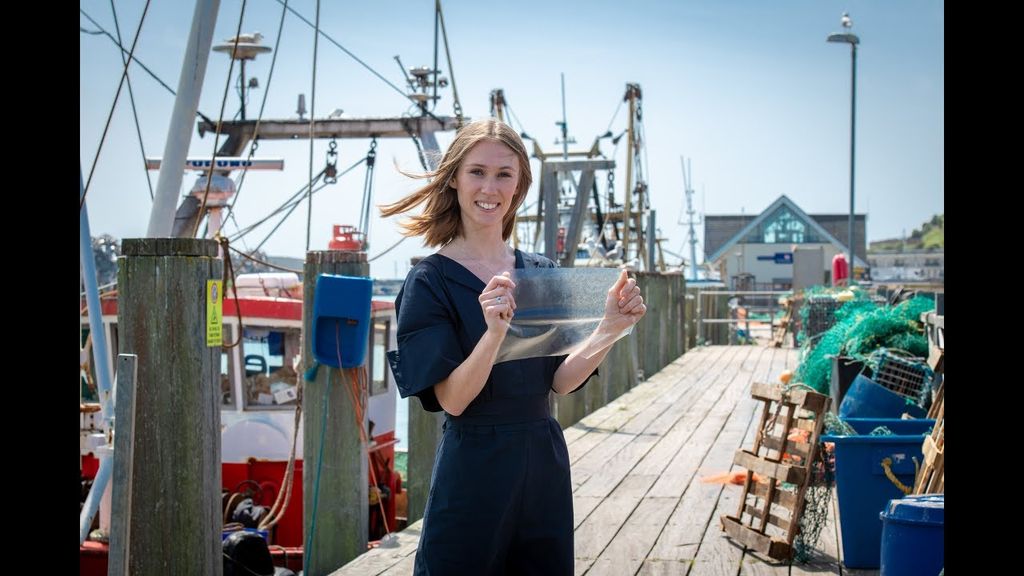 Lucy Hughes poses on a dock with a sheet of MarinaTex.