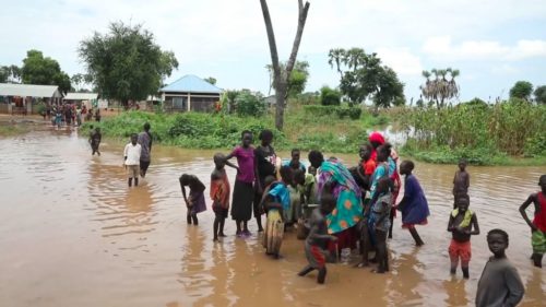 View of women and children at flooded water pump in flooded South Sudan village.