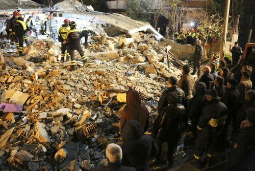A crowd looks on as rescuers sort through rubble after the earthquake in Albania.