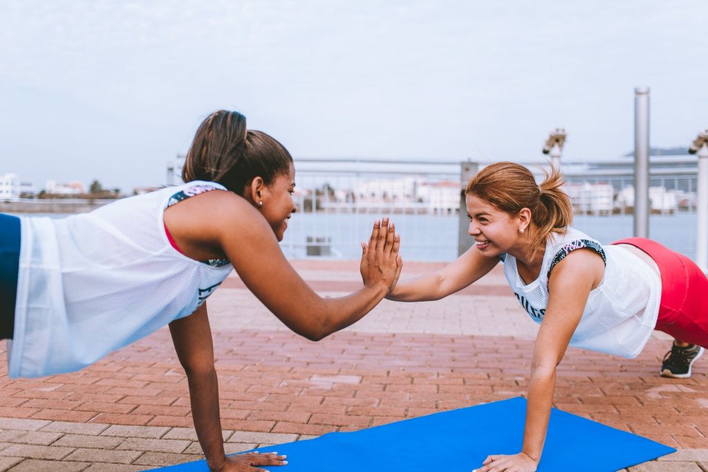 Two girls high five while doing pushups.