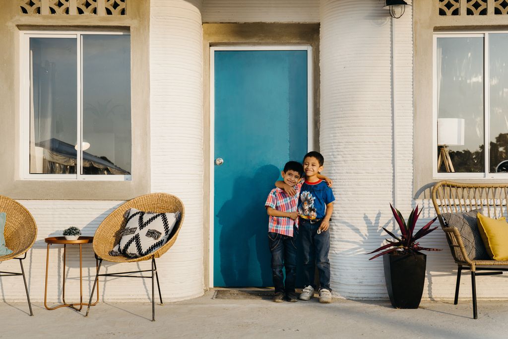 Boys in front of a 3D-printed house in Tabasco, Mexico created by Icon and New Story.