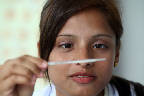 A Health Worker Manisha C.K is checking the temperature on a thermometer. Batulechaur Health Post, Pokhara, Nepal.