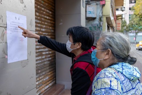 Street photo in Guangzhou - two people wearing face masks looking at a notice, presumably about the coronavirus.