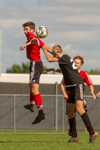 Boys in air struggling to head soccer ball.