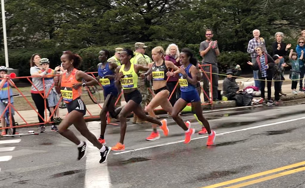 Chasing group of women, including second place finisher w:Edna Kiplagat and third-place w:Jordan Hasay, behind the eventual winner Worknesh Degefa who was already well ahead, at Walnut street just past Mile 19 during the 2019 Boston Marathon.