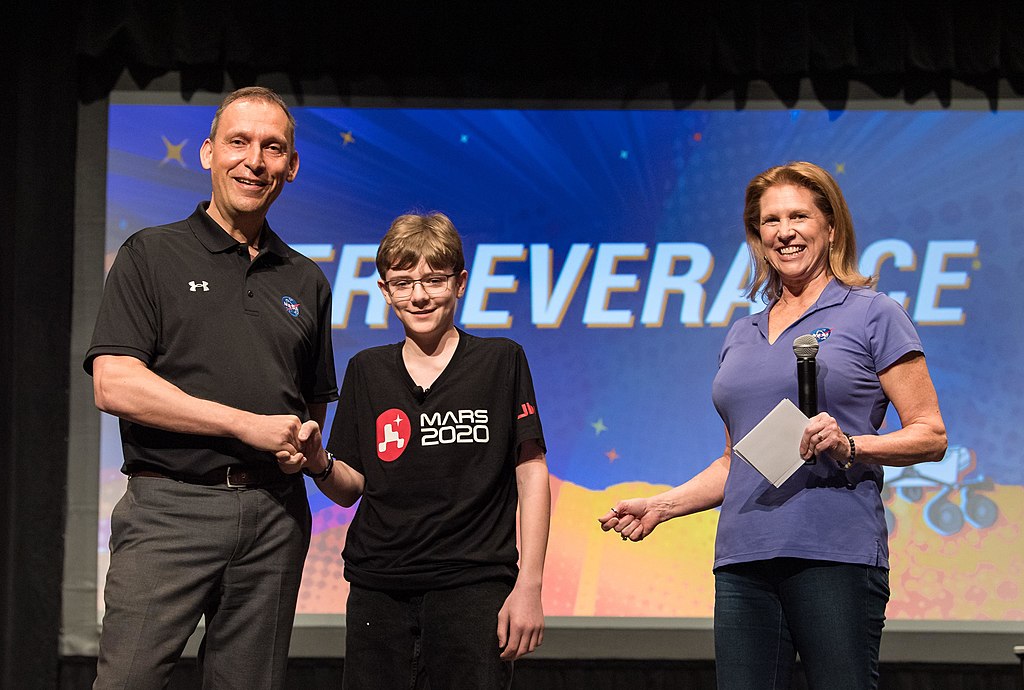 Lori Glaze, director of NASA's Planetary Science Division, looks on as Thomas Zurbuchen, associate administrator of NASA's Science Mission Directorate, congratulates Alexander Mather on March 5, 2020, during a celebration at Lake Braddock Secondary School in Burke, Virginia.