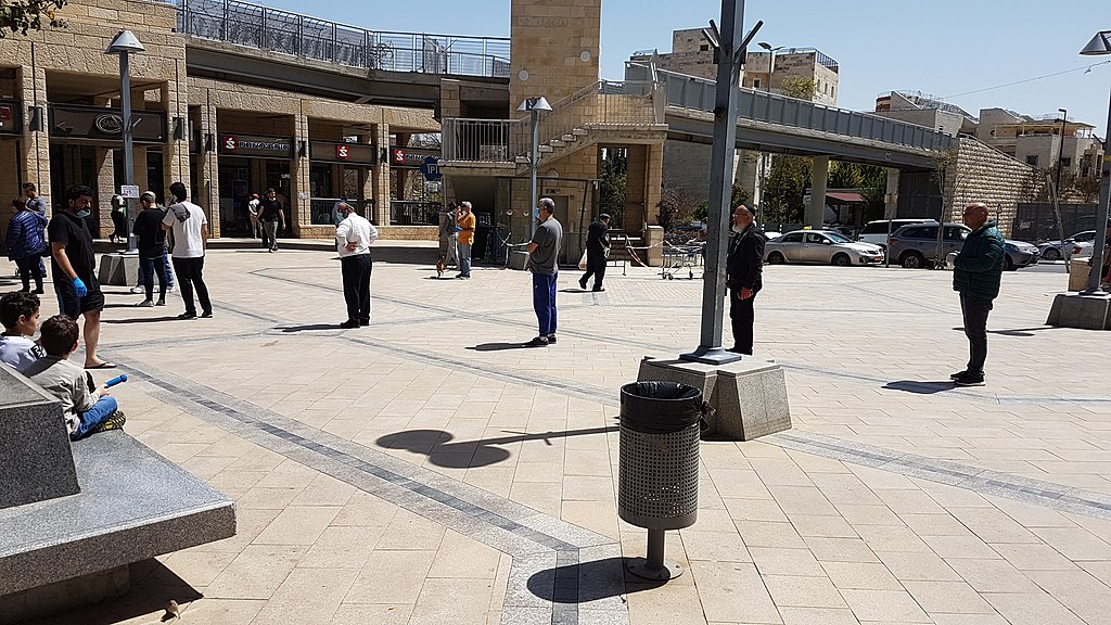 A queue of people applying physical social distancing outside of a supermarket in Jerusalem