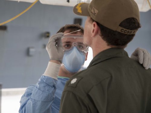 U.S. Navy Hospital Corpsman takes a sample of a Sailor embarked aboard the aircraft carrier USS Theodore Roosevelt to be tested for COVID-19 April 20, 2020.