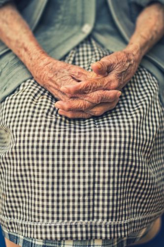 Shot of an old woman's hands folded in her lap.