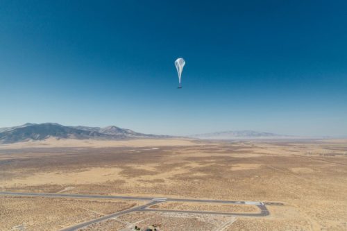 A Loon balloon is seen over a wide open landscape.
