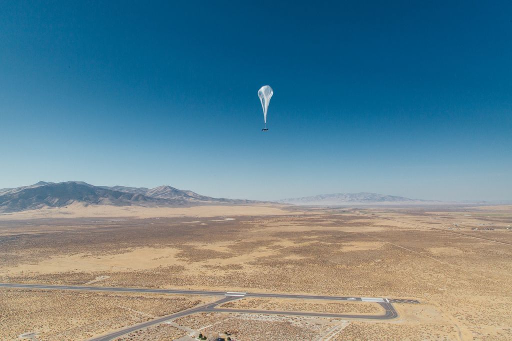 A Loon balloon is seen over a wide open landscape.