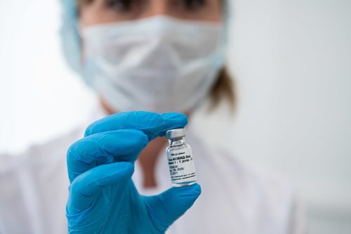 A masked healthcare worker holds up a vial containing the Russian vaccine for the coronavirus. Vaccination of medical workers in Moscow
