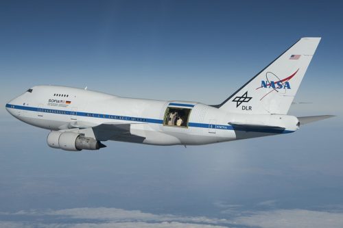 NASA's SOFIA Flying Infrared Observatory - an airplane flying through the sky with an observation port open near the tail.