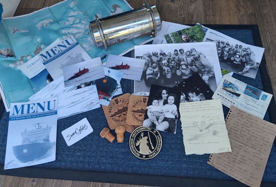 Items from the time capsule spread out, including a map, menus, photographs, postcards, and letters..
