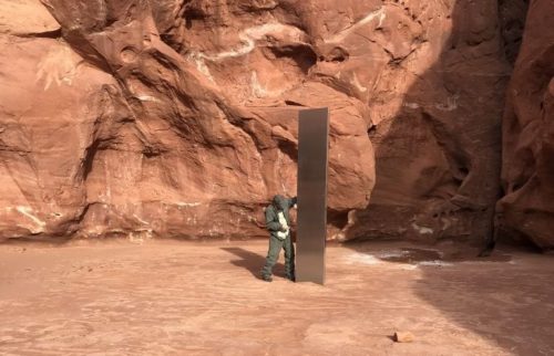 A worker stands beside the metal monolith found in the Utah desert.