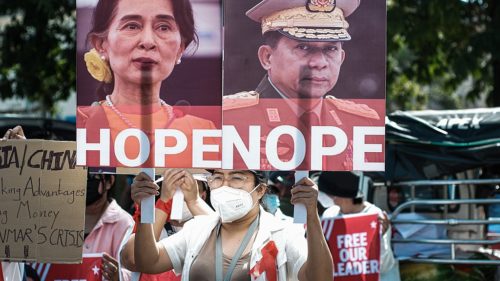 Protest in Myanmar against Military Coup 14-Feb-2021 - protester holding sign with images of Aung San Suu Kyi marked 'hope' and General Min Aung Hlaing, marked 'nope'.