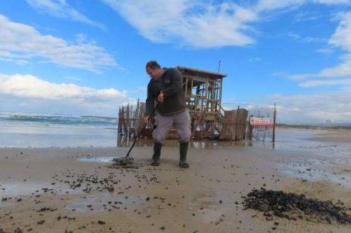 A man works to clean tar balls off of a beach in Israel.