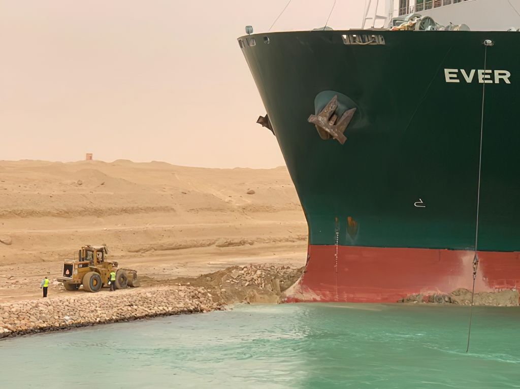 Bulldozer on shore in front of the mega container ship Ever Given.