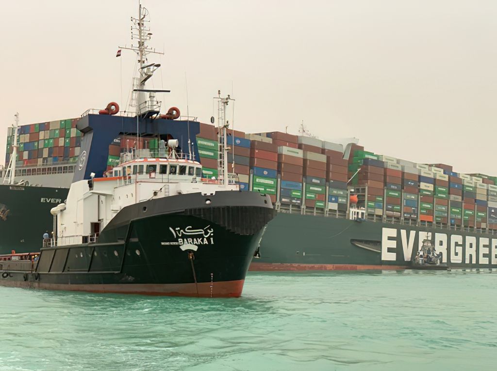 A boat attempting to tow the mega container ship Ever Given.