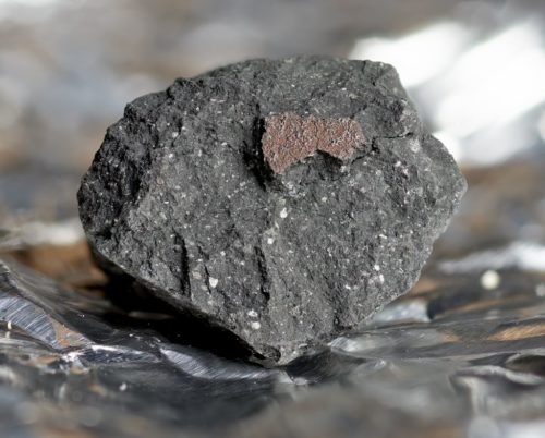 A close-up of a carbonaceous chondrite meteorite found in the UK. The rock is sitting on foil.