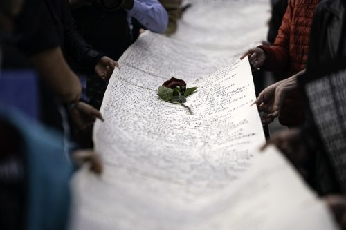 Participants in a silent march for justice for George Floyd in downtown Minneapolis, Minnesota hold a scroll of names of people killed by police on the day before the beginning of the trial of Derek Chauvin