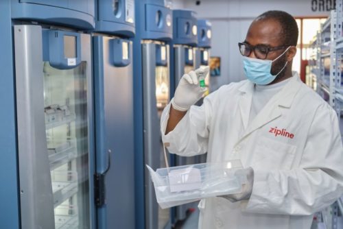 A pharmacist looks at a bottle of AstraZeneca vaccine.