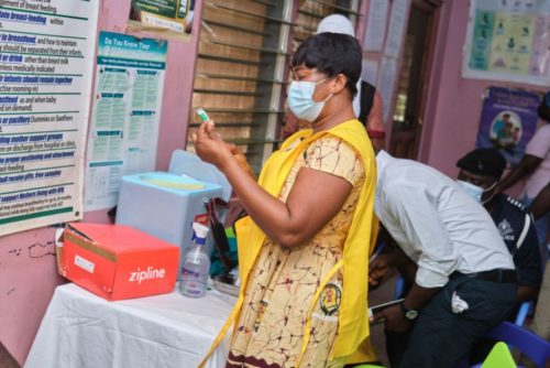 A medical worker prepares to give a vaccine that was dropped by a Zipline drone.