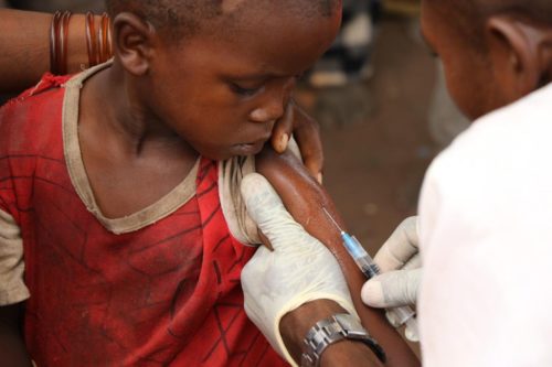 A young child looks on as he is given a vaccination.