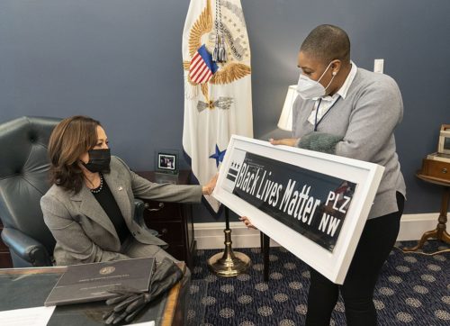 Chief Spokesperson for the Vice President Symone Sanders shows Vice President Kamala Harris a Black Lives Matter street sign Tuesday, Feb. 16, 2021, in her West Wing Office of the White House. The sign is a gift from DC Mayor Muriel Bowser. (Official White House Photo by Lawrence Jackson)