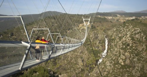 The 516 Arouca bridge in Portugal's Arouca Geopark. View from side, with people looking over the side in the foreground.
