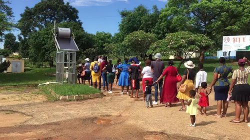 A line of people wait to wash their hands at a hot water station at a health clinic in Lomamba, eSwatini.