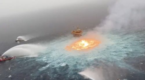 Screenshot from video showing three ships spraying water on a fire coming out of the ocean near a Pemex oil rig.