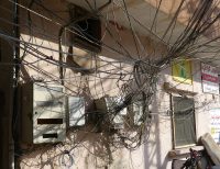 A muddle of power cables on a residential building with a yellow Hezbollah poster on the right in the Southern Lebanese city of Tyre/Sour.