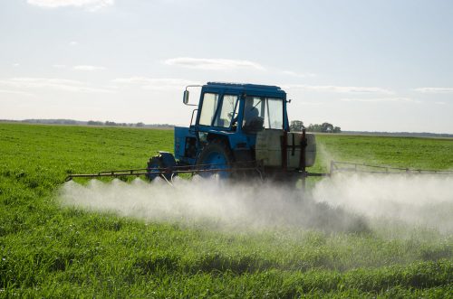 Tractor spraying a field with chemicals.