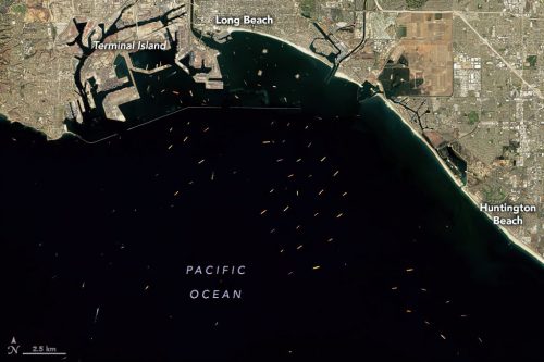 View from space of 87 container ships near the Port of Los Angeles and Port of Long Beach in Southern California, the two busiest container ports in the United States on October 10, 2021. Twenty-seven ships were in berths and 60 were waiting (either anchored or floating in drift zones) offshore. The number of ships waiting was down from a record-high of 73 on September 19, 2021. The two ports have had unusually large numbers of waiting ships since June 2020. Before then, cargo ships rarely waited to unload. (Source: Josh