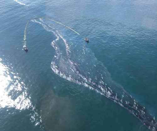 Aerial view showing Coast Guard ships laying a retaining boom during the oil spill off the coast of Orange county, California on October 3, 2021.