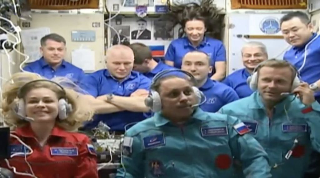 Yulia Peresild, Anton Shkaplerov, and Klim Shipenko (front row) seen on the ISS along with other members of the space station crew during a video meeting.