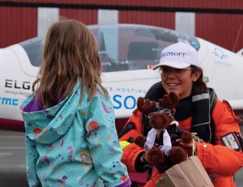 Zara Rutherford talks to a young girl in front of her plane.