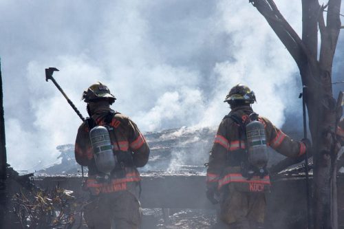 Fire fighters look out at a landscaped masked by smoke from a forest fire.