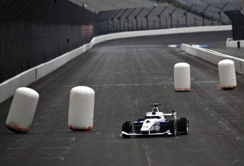 Indy Autonomous Challenge: A self-driving car passes inflatable obstacles on the track.