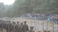 Polish soldiers march on one side of the border, while migrants work to tear down the fence on the other.