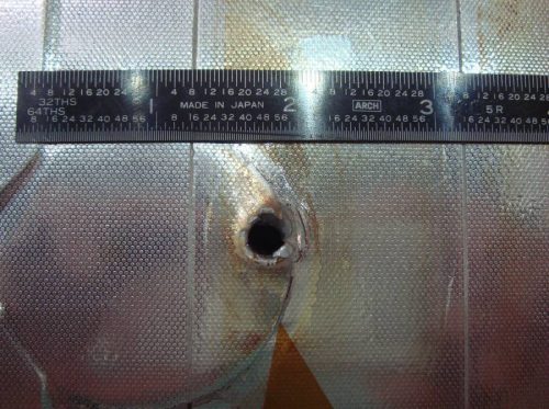 Image of the entry hole created on Space Shuttle Endeavour's radiator panel by the impact of unknown space debris.